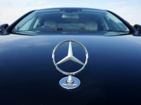 Close-up of a Mercedes-Benz emblem on a luxury car hood featuring a sleek design.